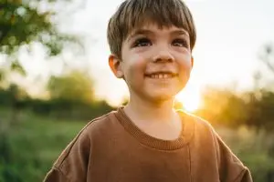 Smiling young boy outdoors in warm evening sunlight